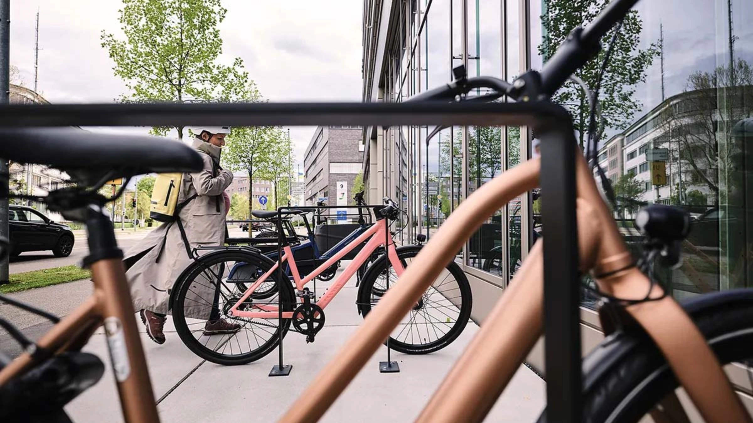 Rows of bicycles parked in a structured stand near a workplace